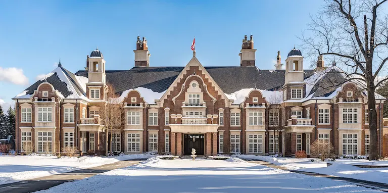 A Tudor-style brick and stone manor with tall chimneys behind a snow-covered lawn