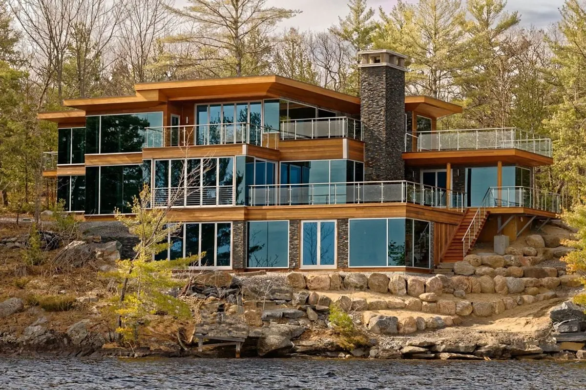 A modern timber and glass cottage standing on a rocky island shoreline