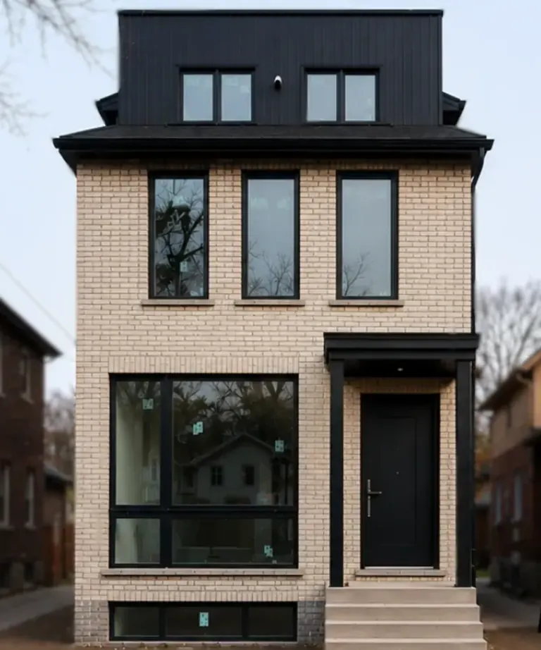 Finished pale brick infill home with black window frames and a black upper storey, standing between two older houses