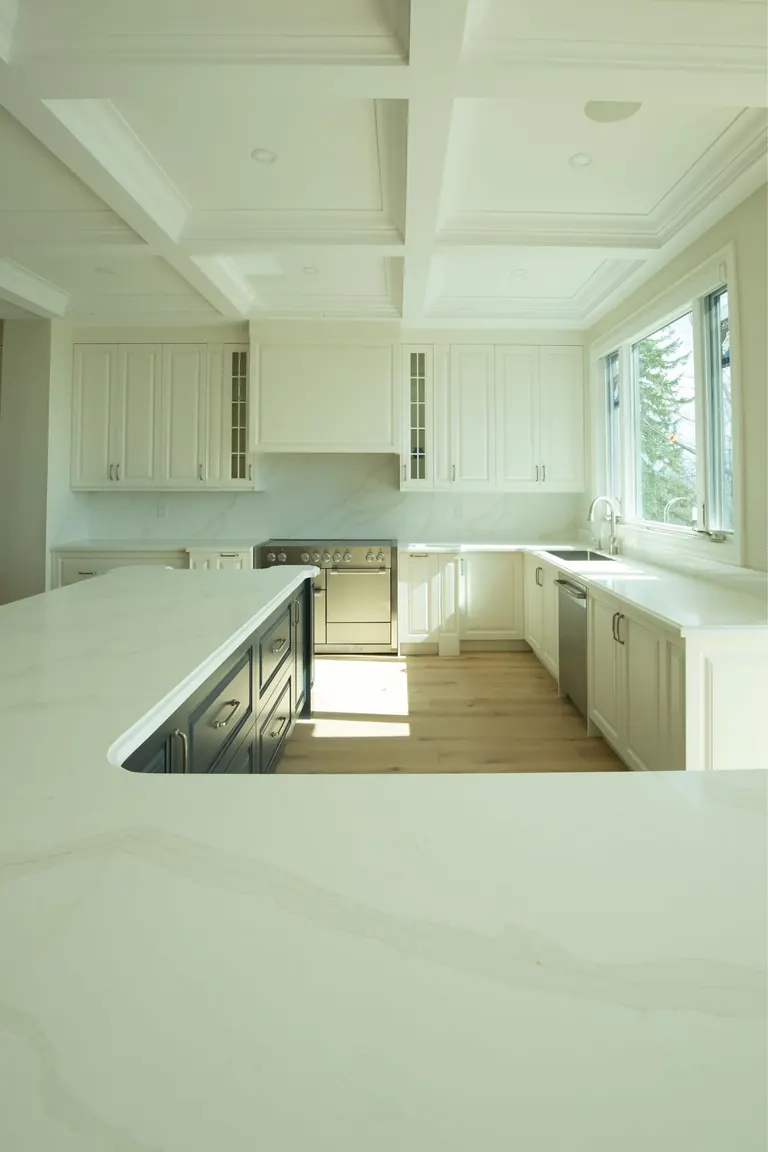 Finished kitchen under a coffered ceiling, seen across a marble island