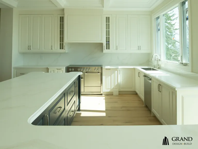 Finished kitchen with cream cabinetry, a navy island and marble counters