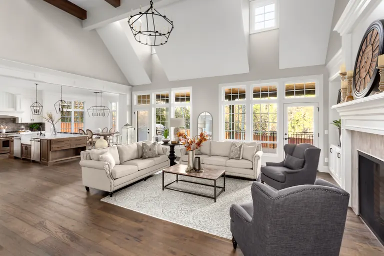 A finished great room under a vaulted ceiling with exposed beams, open through to the kitchen beyond and glazed doors onto a deck