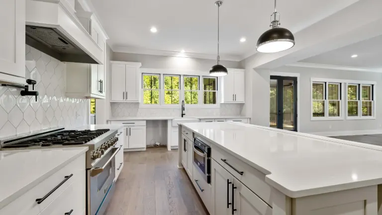 Finished white kitchen with a large island, range and pendant lighting